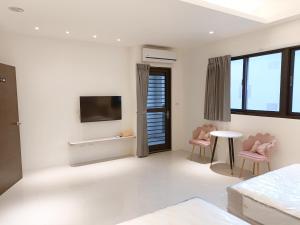 a white bedroom with pink chairs and a tv at Penghu Michi Homestay in Hsing-wen +12 photos