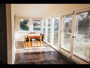 a dining room with a table and chairs and windows at Pooh Corner, Cottage in Robe +8 photos