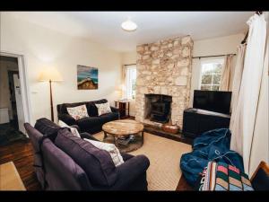 a living room with couches and a stone fireplace at Pooh Corner, Cottage in Robe