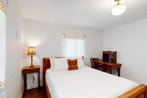 a bedroom with a white bed and a desk with a lamp at Lazy C Ranch in Tucson