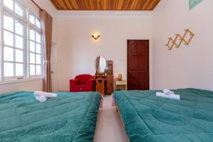 - une chambre avec deux lits et une chaise rouge dans l'établissement Villa Trung nghĩa 28, à Đà Lạt