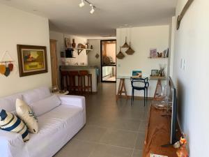 a living room with a white couch and a kitchen at Amável Village de 2 suites, pé na areia em Itacimirim, Praia do Forte, Bahia in Camaçari