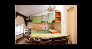 una cocina con armarios verdes, mesa y sillas en 777 Apartments 2, en Cracovia