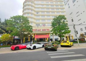 een groep auto's geparkeerd voor een gebouw bij Viet Uc Hotel in Ben Tre