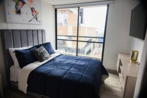a bedroom with a blue bed and a large window at Downtown Bogota Centro Internacional in Bogotá +32 photos