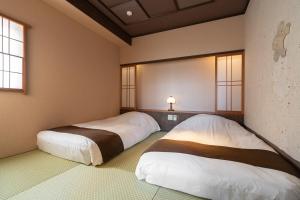 2 Betten in der Ecke eines Zimmers in der Unterkunft Tokinoniwa in Kusatsu