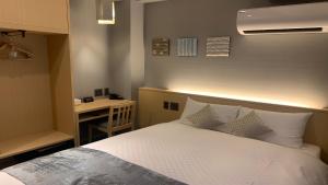 a bedroom with a bed with white pillows and a desk at KYOTO GION HOTEL in Kyoto