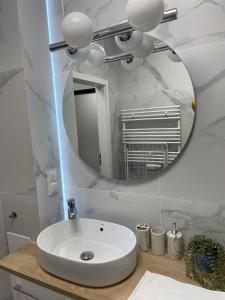 a bathroom with a white sink and a mirror at Apartament Silence Karpatia Resort Tanzanit in Karpacz