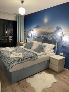 a bedroom with a large bed with a painting on the wall at Apartament Silence Karpatia Resort Tanzanit in Karpacz
