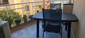 a black table and chair sitting on a balcony at 65 Rue Pierre Rameil Appartement in Cavalaire-sur-Mer