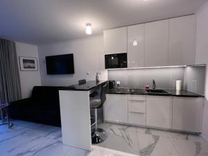 kuchnia z białymi szafkami i czarnym blatem w obiekcie Apartament Kasprowicza 12A w Kołobrzegu