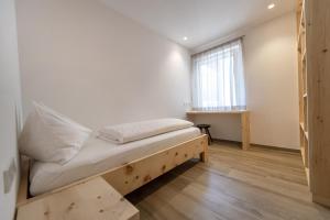 um pequeno quarto com uma cama e uma janela em Apartment Dauru em Ortisei