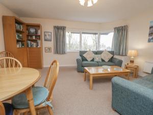 Una sala de estar con un sofá azul y una mesa. en Treetops, en Windermere