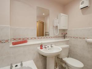 Un baño blanco con inodoro y lavabo. en Treetops, en Windermere 27 fotos más