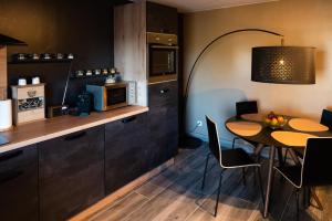 - une cuisine et une salle à manger avec une table et un four micro-ondes dans l'établissement Le Refuge, à Namur