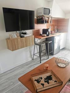 ein Wohnzimmer mit einer Küche mit einem Tisch und einem TV in der Unterkunft Just Suite Home - Superbe 2 pièces entre Paris et Orly, jardin privé in Villeneuve-Saint-Georges