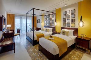 Habitación de hotel con 2 camas y escritorio en Allegro Hoi An . A Little Luxury Hotel & Spa en Hoi An