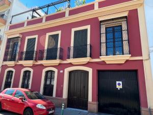 un edificio rojo con un coche rojo estacionado frente a él en Teodosio Apartment FREE PARKING & CENTRAL AC, en Sevilla