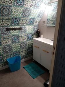 baño con lavabo y pared de azulejos en À La Maison Du Bonheur, en Audruicq