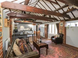 a living room with a couch and a kitchen at Old Cart Shed in Lyneham