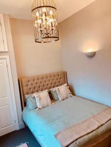 Una cama en un dormitorio con una lámpara de araña. en NiCheGetaway, en Shrewsbury