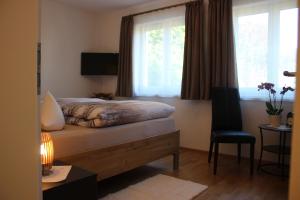 a bedroom with a bed with a window and a chair at Steppacher Ferienappartements in Friedenweiler