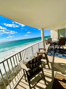 balkon z krzesłami i stołami oraz plaża w obiekcie Emerald Bay Escape w mieście Panama City Beach