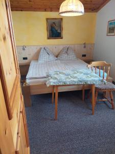 a bedroom with a bed with a table and a chair at Ferienwohnung Muhlbauer in Wald im Pinzgau