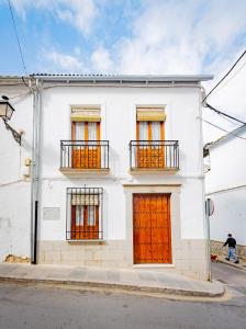 a white building with orange doors on a street at CASA EL RINCONCITO in Antequera