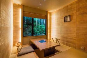 Zimmer mit einem Tisch, Stühlen und einem Fenster in der Unterkunft Toushinan Komeya in Ito