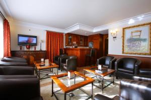una sala de espera con mesas y sillas de cuero negro en Hotel El Juglar, en Olite