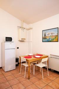 una cucina con tavolo in legno e frigorifero bianco di Residence San Raffaele 1 a Milano