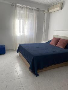 a bedroom with a bed with a blue blanket and a window at Hermoso piso/apartamento amueblado patraix Valencia. in Valencia
