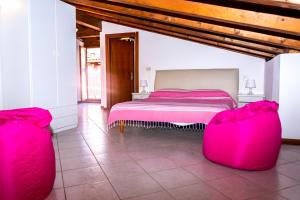 a bedroom with a pink bed and two red chairs at Hotel Villa Rosa in Porto Azzurro