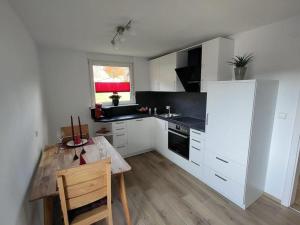 cocina con armarios blancos y mesa de madera en Black Forest Birdnest en Schonach