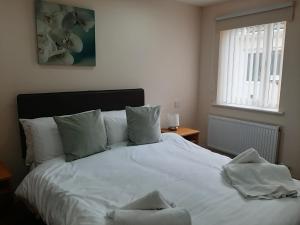 a bedroom with a white bed with pillows and a window at Holly Lodge in Alnwick