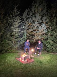 two men sitting around a fire pit at night at Hotel boutique Garden Resort by Brancoveanu in Moieciu de Jos