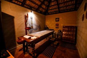 Habitación pequeña con cama y mesa de madera. en Veda5 Ayurveda Living Village, en Trichūr