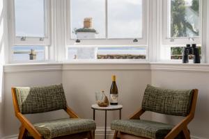 Culross的住宿－The Dundonald Guesthouse & Cottage，带窗户的客房内配有两把椅子和一瓶葡萄酒