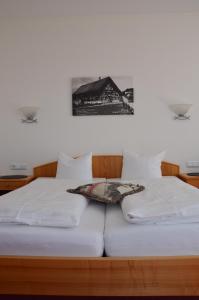 a bed with white sheets and a picture on the wall at Gasthof Hirschen in Sibratsgfäll
