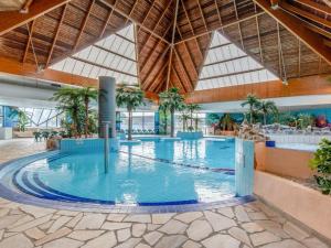 a large swimming pool in a building with trees at l'appartement la Pommeraie in Branville