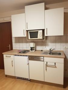 コッヘムにあるGästehaus "Am weißen Stein"の白いキャビネット、シンク、電子レンジ付きのキッチンが備わります。