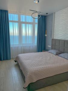 a bedroom with a large bed with blue curtains at Sea View Sky 15 Апартаменти в Одесі in Odesa
