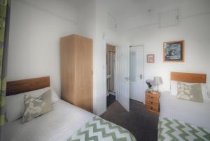 a bedroom with two beds and a wooden cabinet at Lingmoor in Windermere