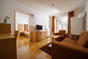 a living room with a couch and a tv at Hotel Garni Toscanina - Adults Only in Bad Radkersburg