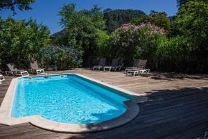 a swimming pool on a deck with chairs and trees at Hôtel Helvie in Vals-les-Bains