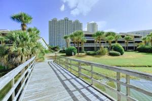 a wooden boardwalk leading to a building with palm trees at Seascape 38A in Destin