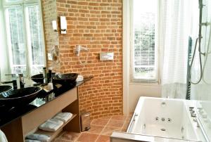 La salle de bains est pourvue de 2 lavabos et d'un mur en briques. dans l'établissement Château D'Apigné Rennes, à Le Rheu