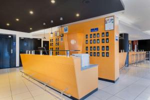 a waiting room with a yellow wall in a building at Comfort Hotel Lille L'Union in Tourcoing