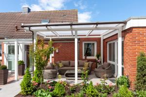 eine weiße Pergola auf einem Backsteinhaus in der Unterkunft Hotel garni NordSeerose Greetsiel in Krummhörn